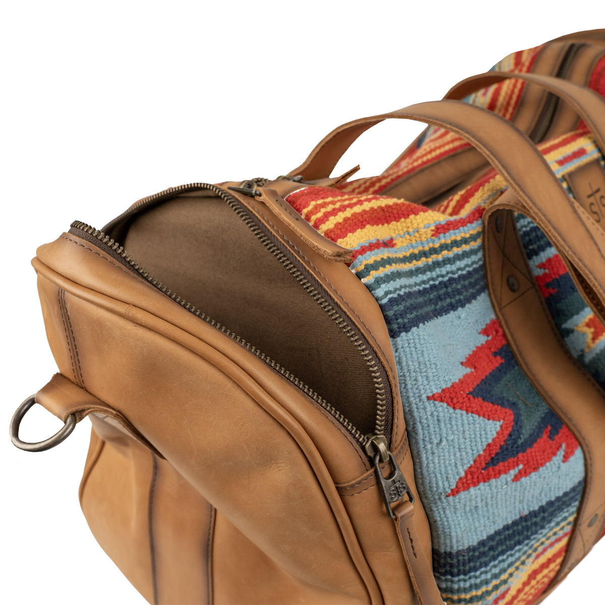Detail of zip pocket on a duffle bag with a vibrant geometric pattern in red, blue, and tan colors.