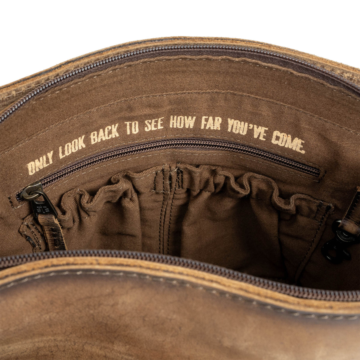 "Only look back to see how far you've come." gold letters printed in the lining of a leather bag.