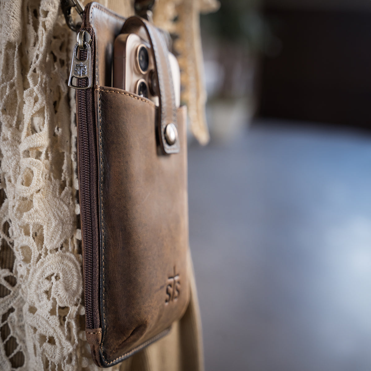 closeup of the back of our leather phone sling with zip around closure, snap flap for phone, and adjustable crossbody strap