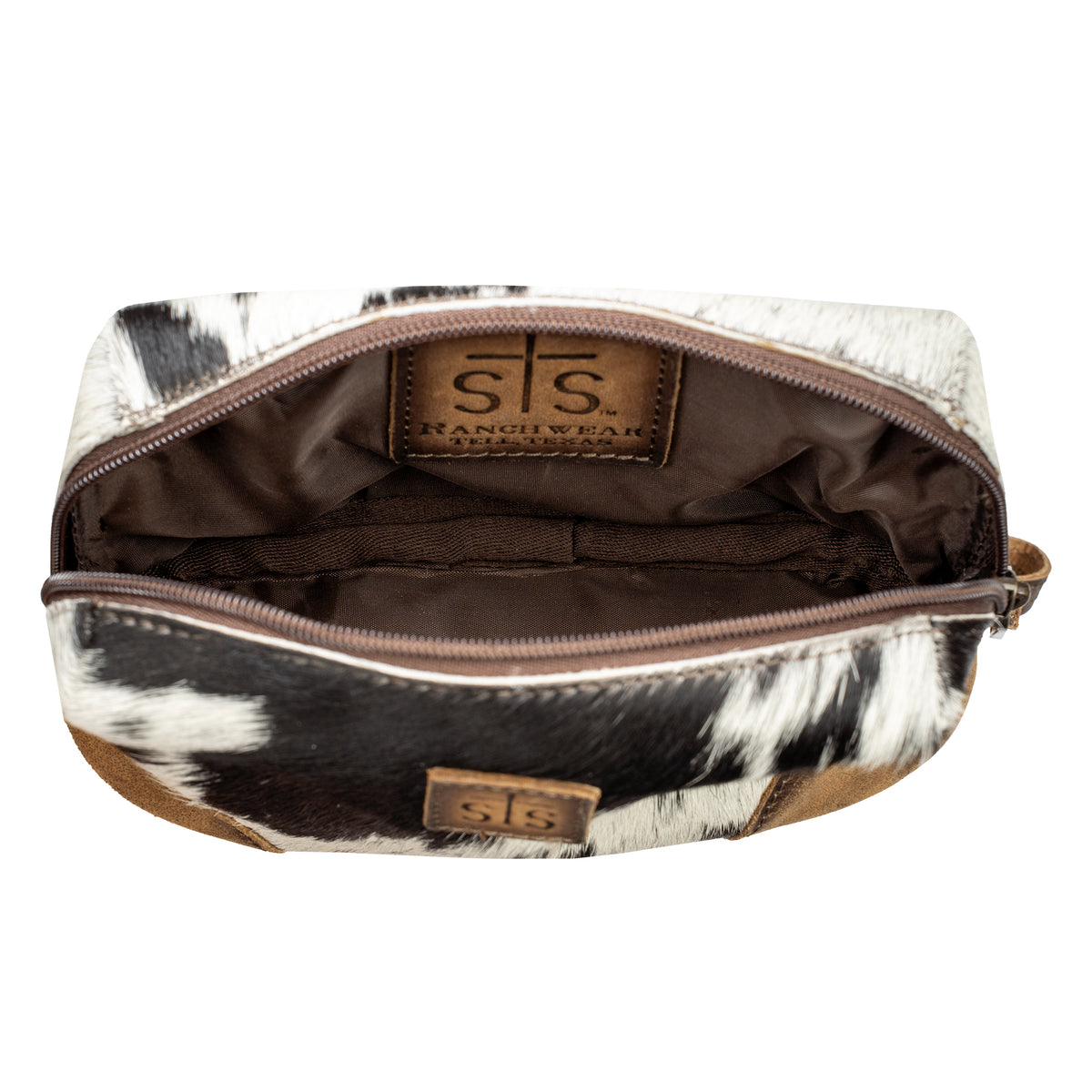 An open zippered cosmetic pouch with a black and white cowhide pattern, brown interior lining and main compartment.