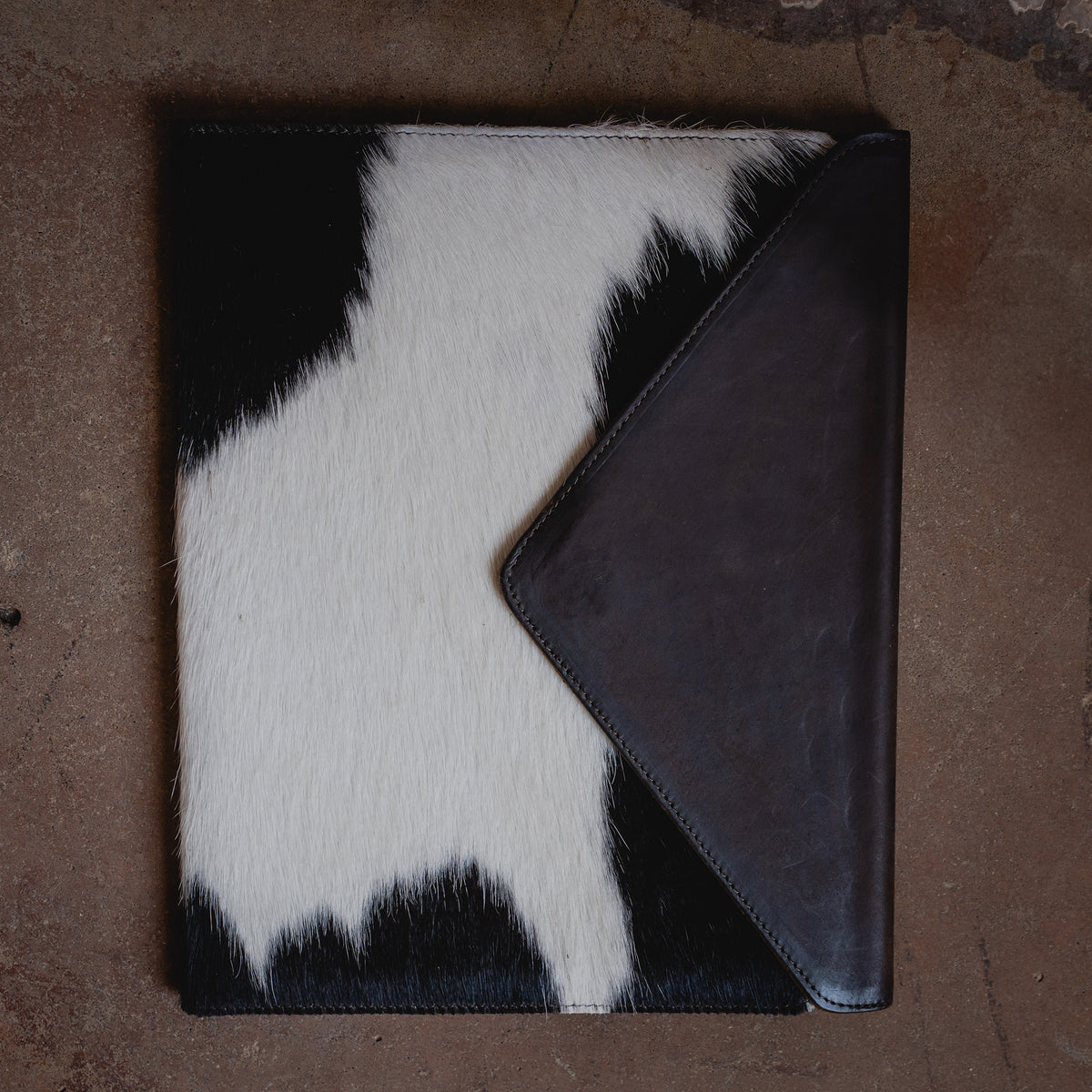 leather and cowhide magnetic closure envelope binder on brown background