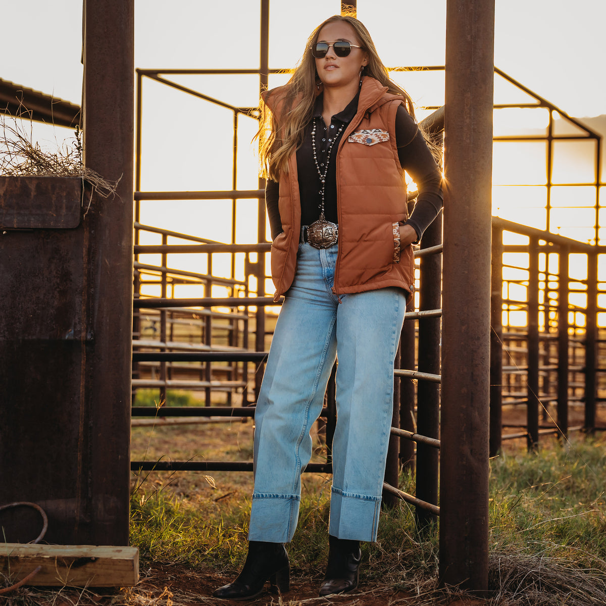 Y'Leigh Yarbrough wearing our rust orange zip up puffer vest with aztec accents and a removable hood outside.