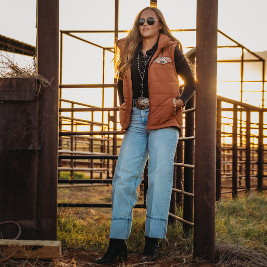 Y'Leigh Yarbrough wearing our rust orange zip up puffer vest with aztec accents and a removable hood outside.