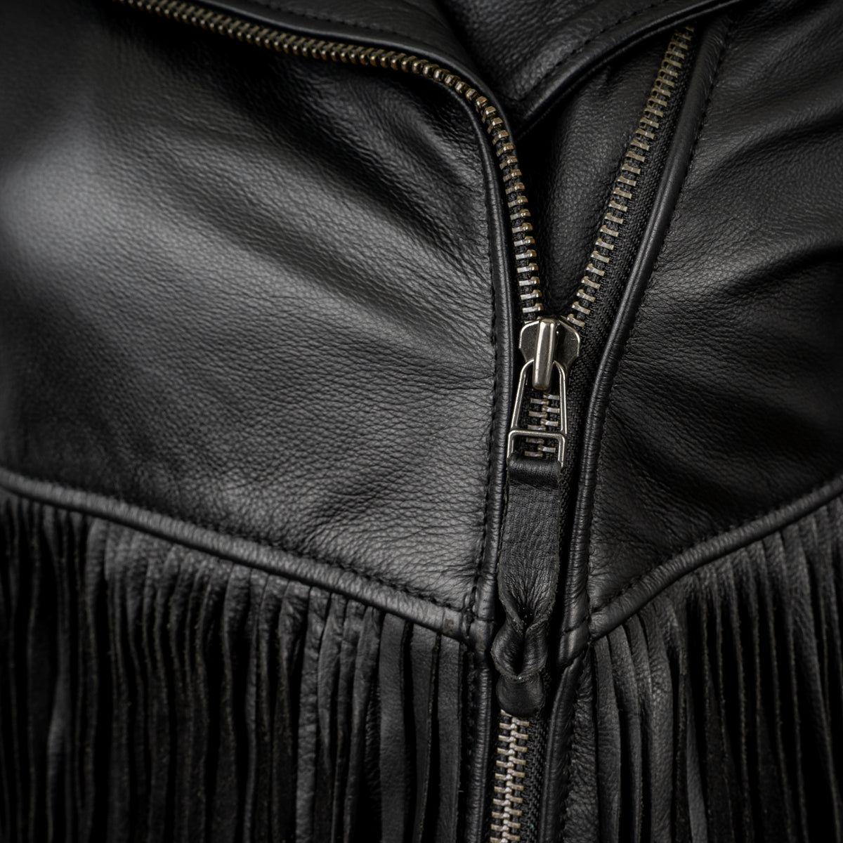closeup of the zipper on our black leather jacket with fringe detailing and asymmetrical zipper front closure