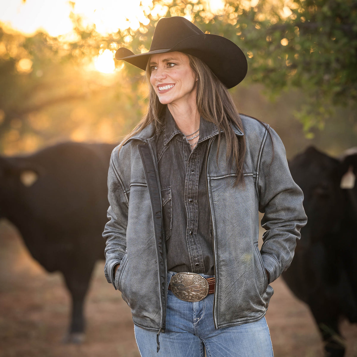 Jennifer Smith wearing the stonewash Rifleman leather jacket with zip closure in front of their black angus cattle.