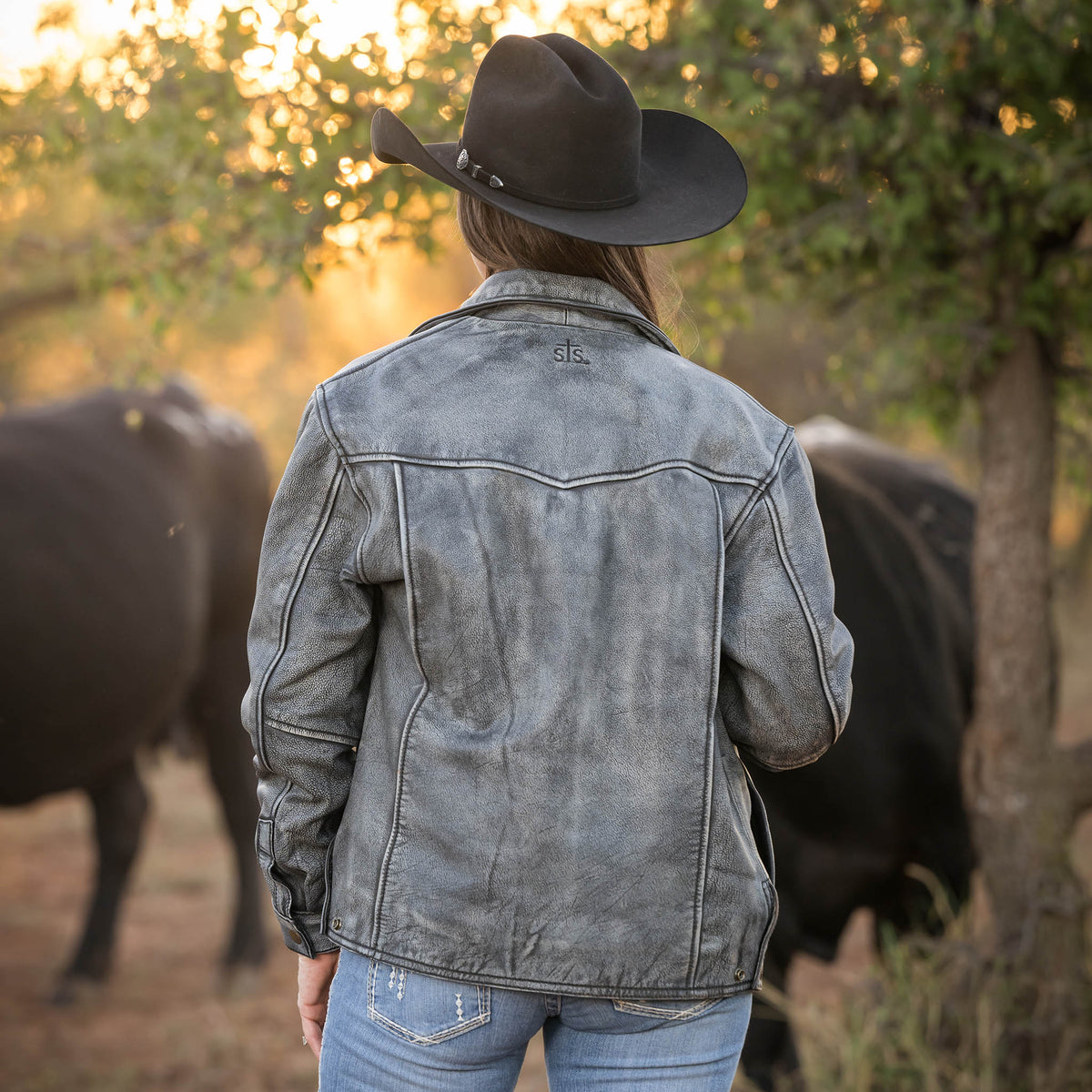 back of Jennifer Smith wearing our stonewash gray women's leather jacket with a classic western cut, featuring a collar, zippered front, and exterior pockets.