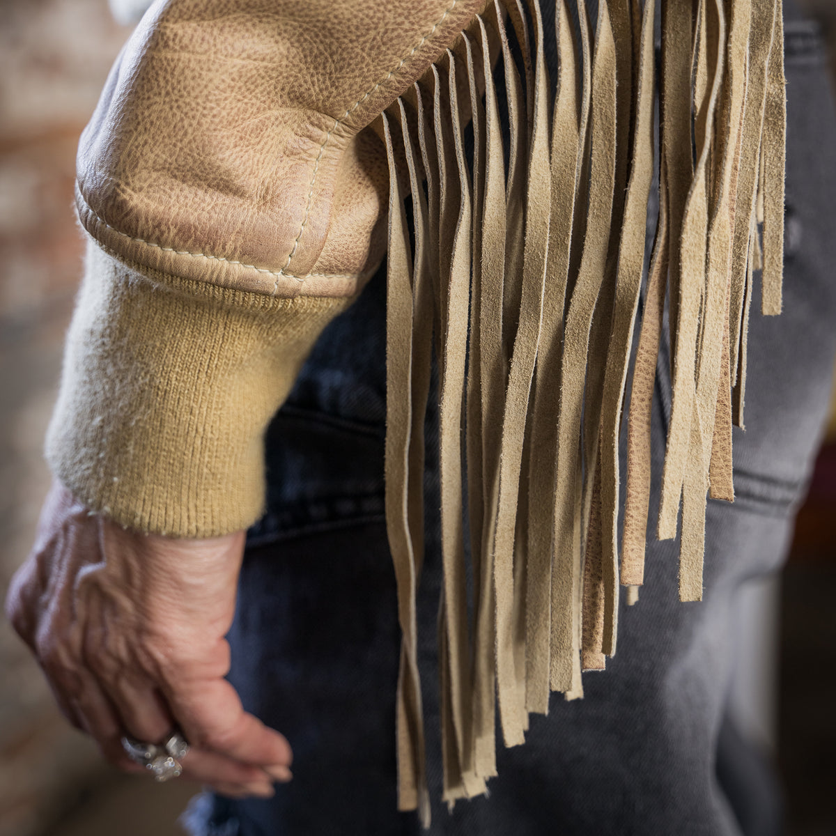 Closeup of the cuff and fringe on our beige leather jacket.