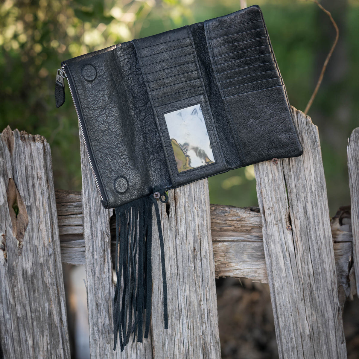 Inside of a black buffalo leather wallet with fringe accents, featuring ID slot, cash slips and card slots.