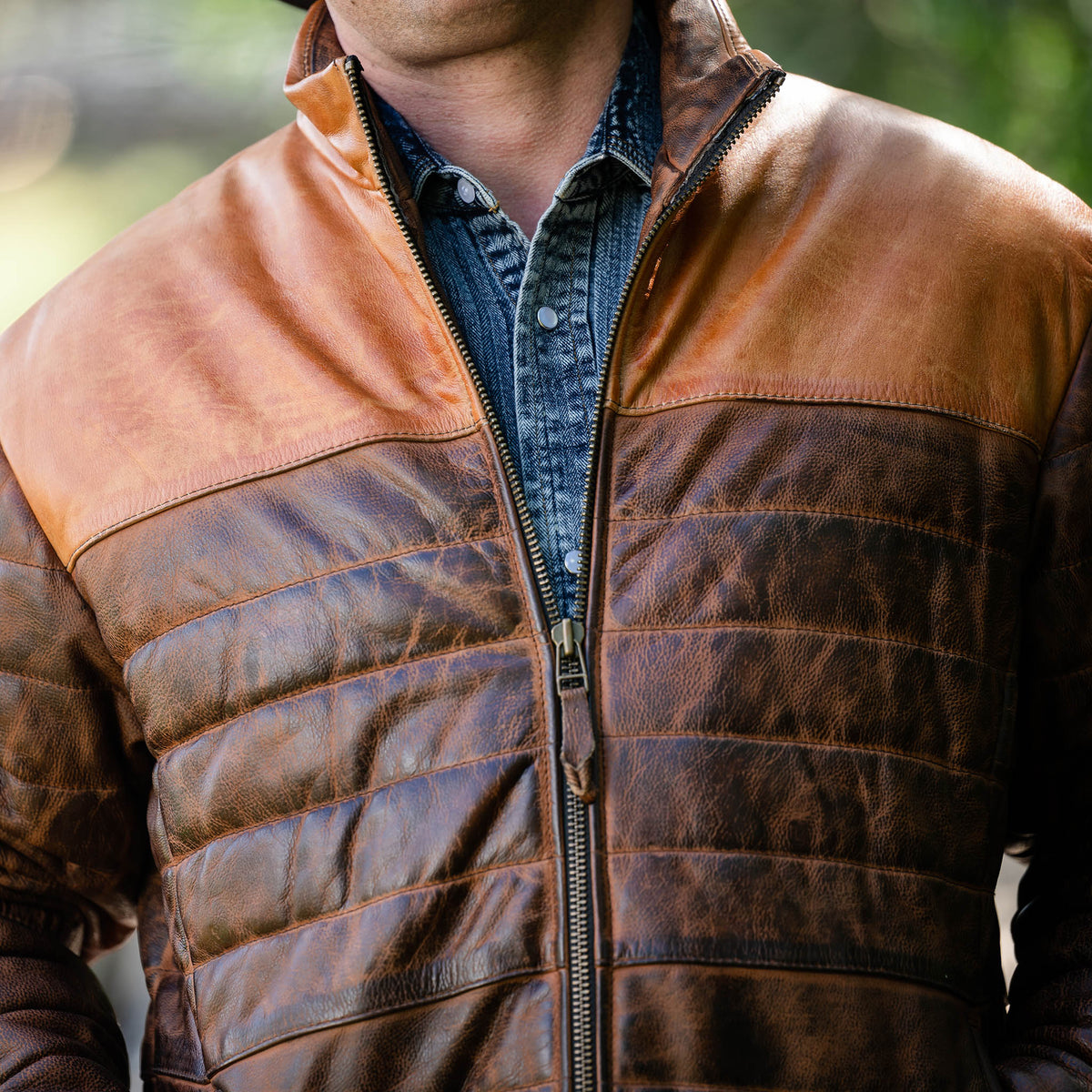 Detail of a brown men's Clyde leather puffer jacket with a full-grain leather exterior and zip front closure.