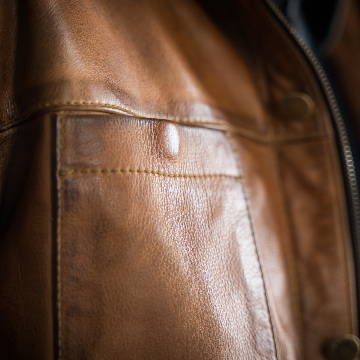closeup of the chest pocket on our brown full grain zip and button front closure with slip hand pockets and chest pockets 