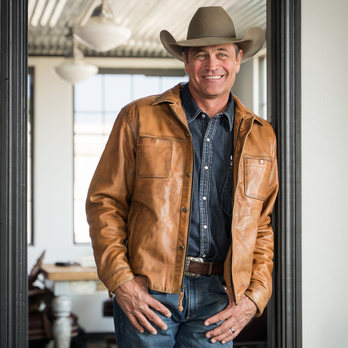stran smith wearing a brown full grain zip and button front closure with slip hand pockets and chest pockets and cowboy hat inside