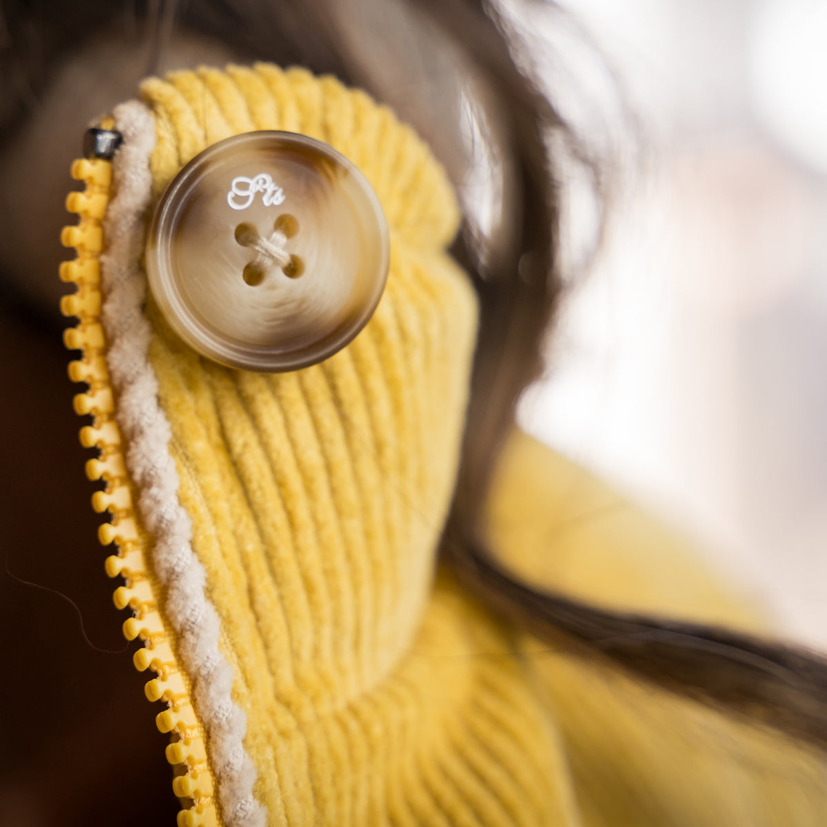 closeup of the bottom at the stop of our cotton color block bomber with zip and button closure 