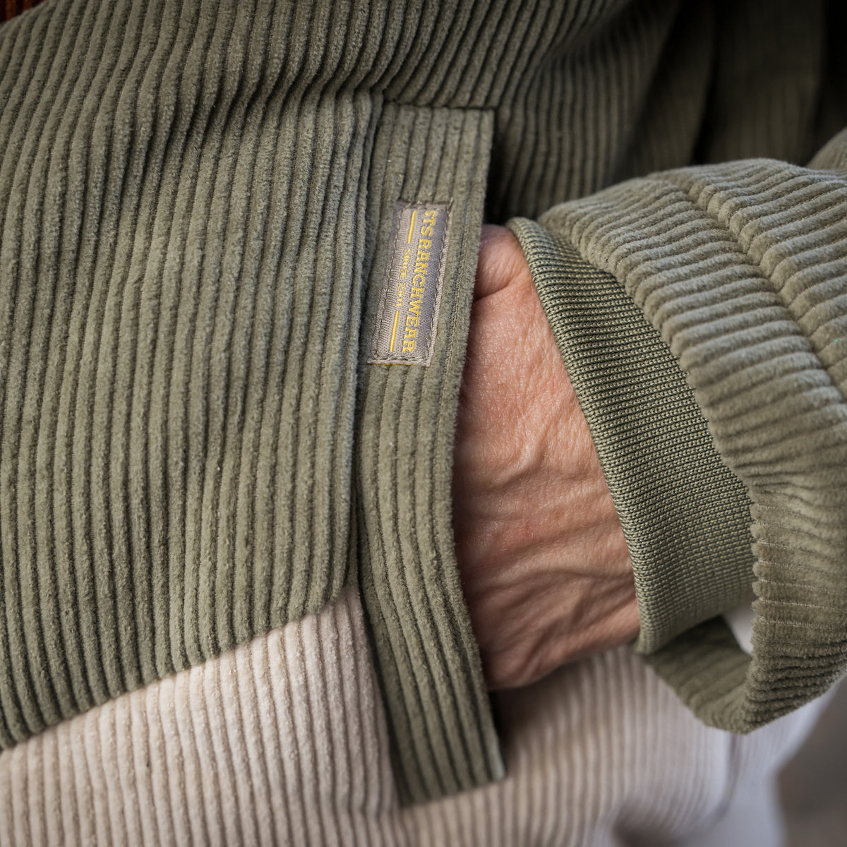 closeup of a hand inside the front pocket of our cotton color block bomber with zip and button closure 