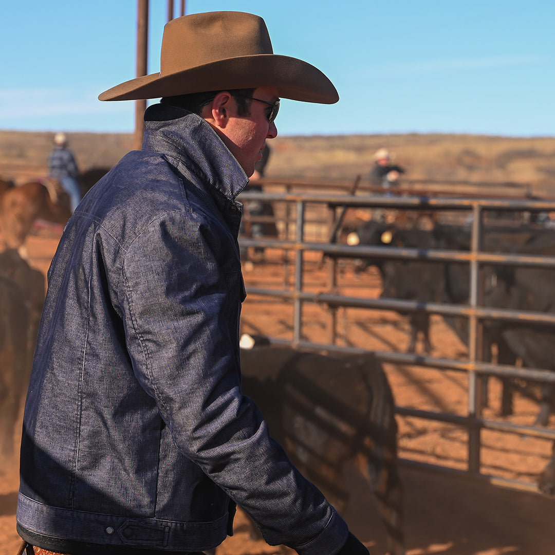 Stran T Smith wearing a brown cowboy hat and long-sleeved blue corduroy jacket working on the ranch in Tell, Texas.
