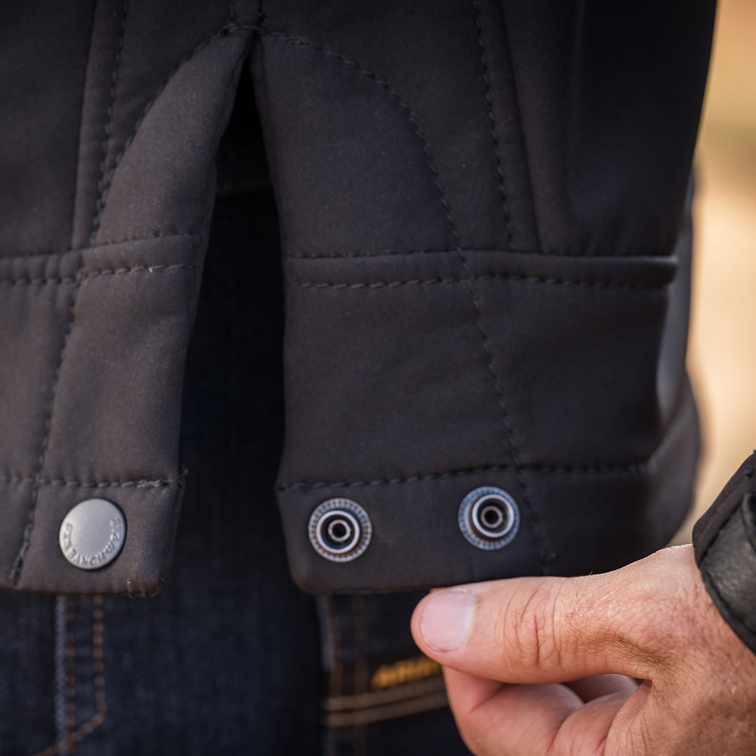close up of the waist snap on the bottom of a black jacket 