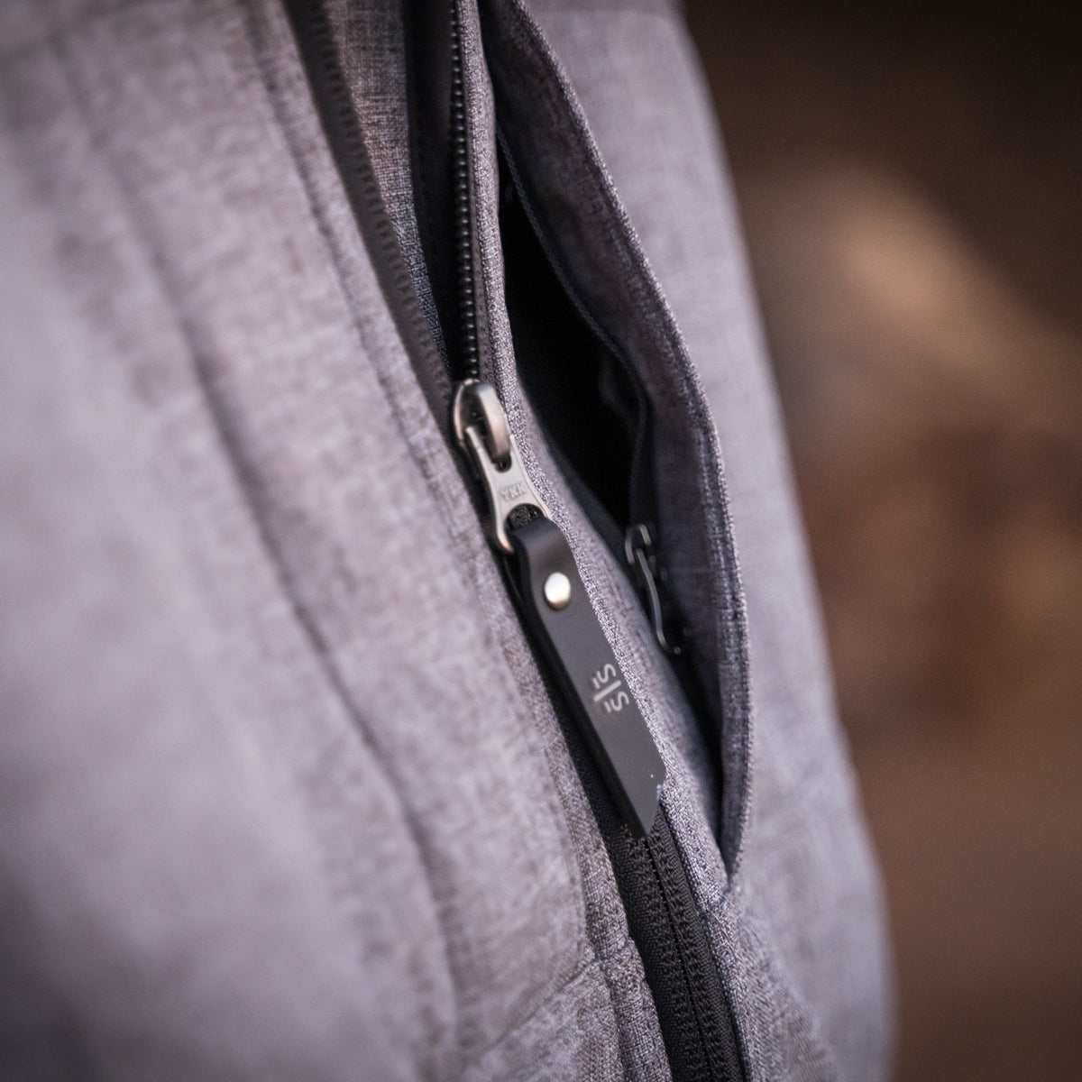 Detail of zipper with black STS zipper pull on gray softshell jacket.