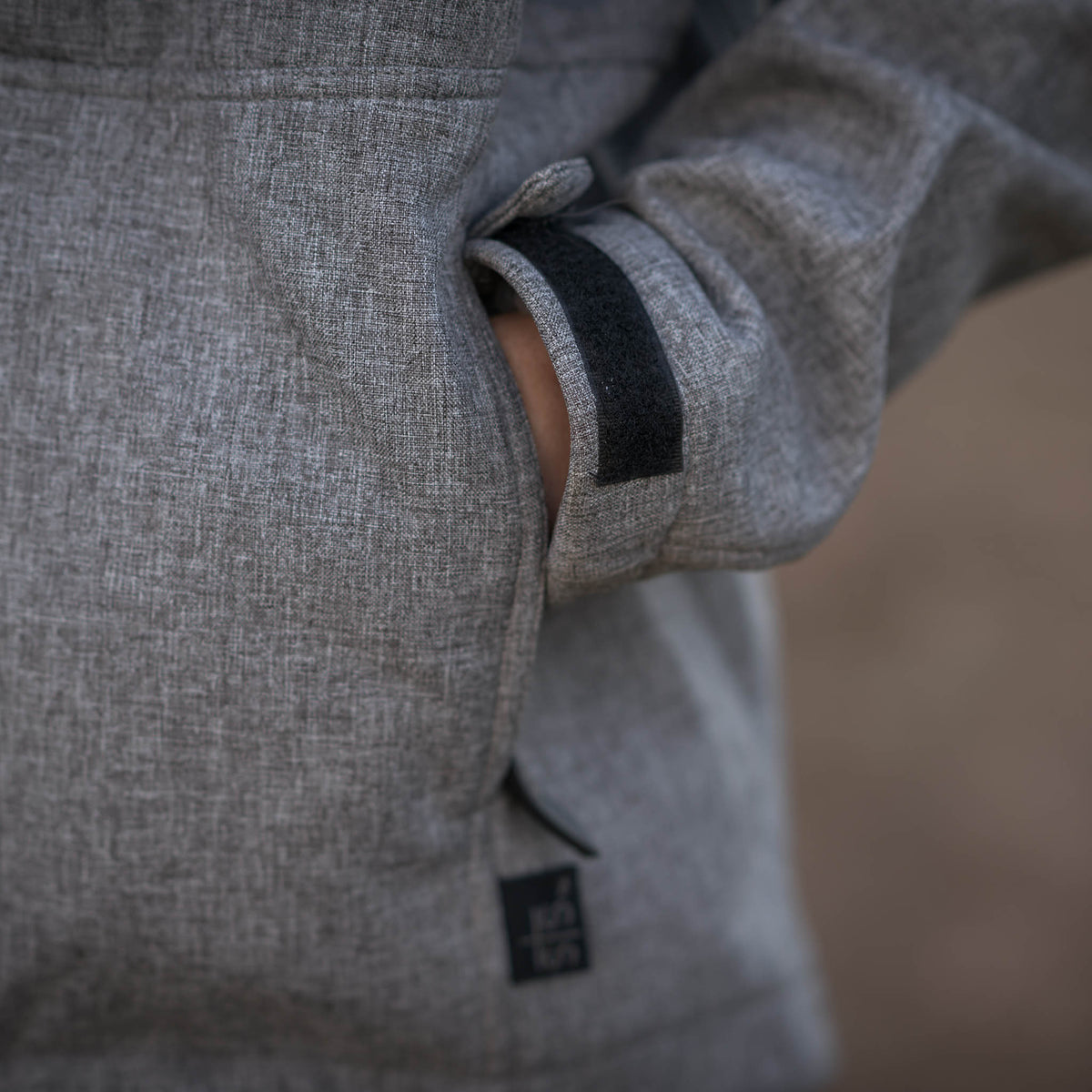 Detail of adjustable velcro wrist cuffs on gray softshell jacket.