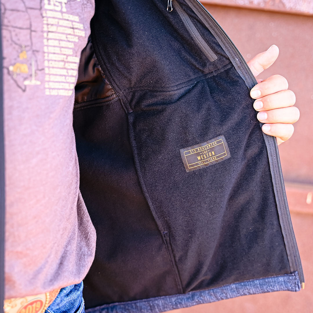 Person holding softshell jacket open showing The Weston tag and fleece lining.