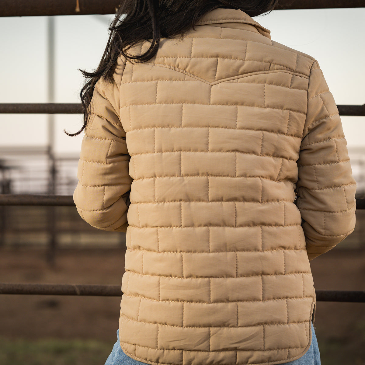 Person facing away wearing a quilted beige jacket.