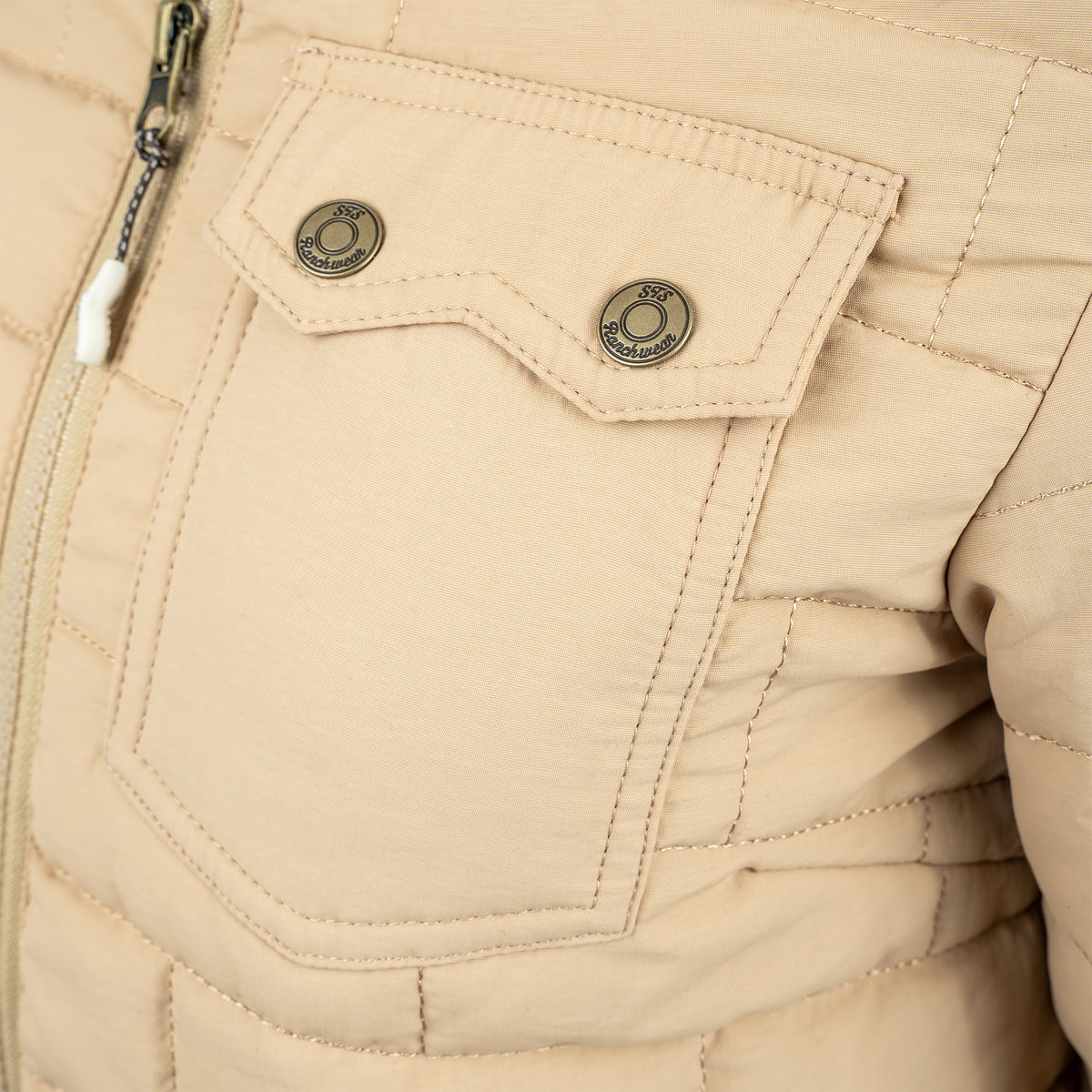Closeup of the front snap closure chest pocket on quilted beige jacket.