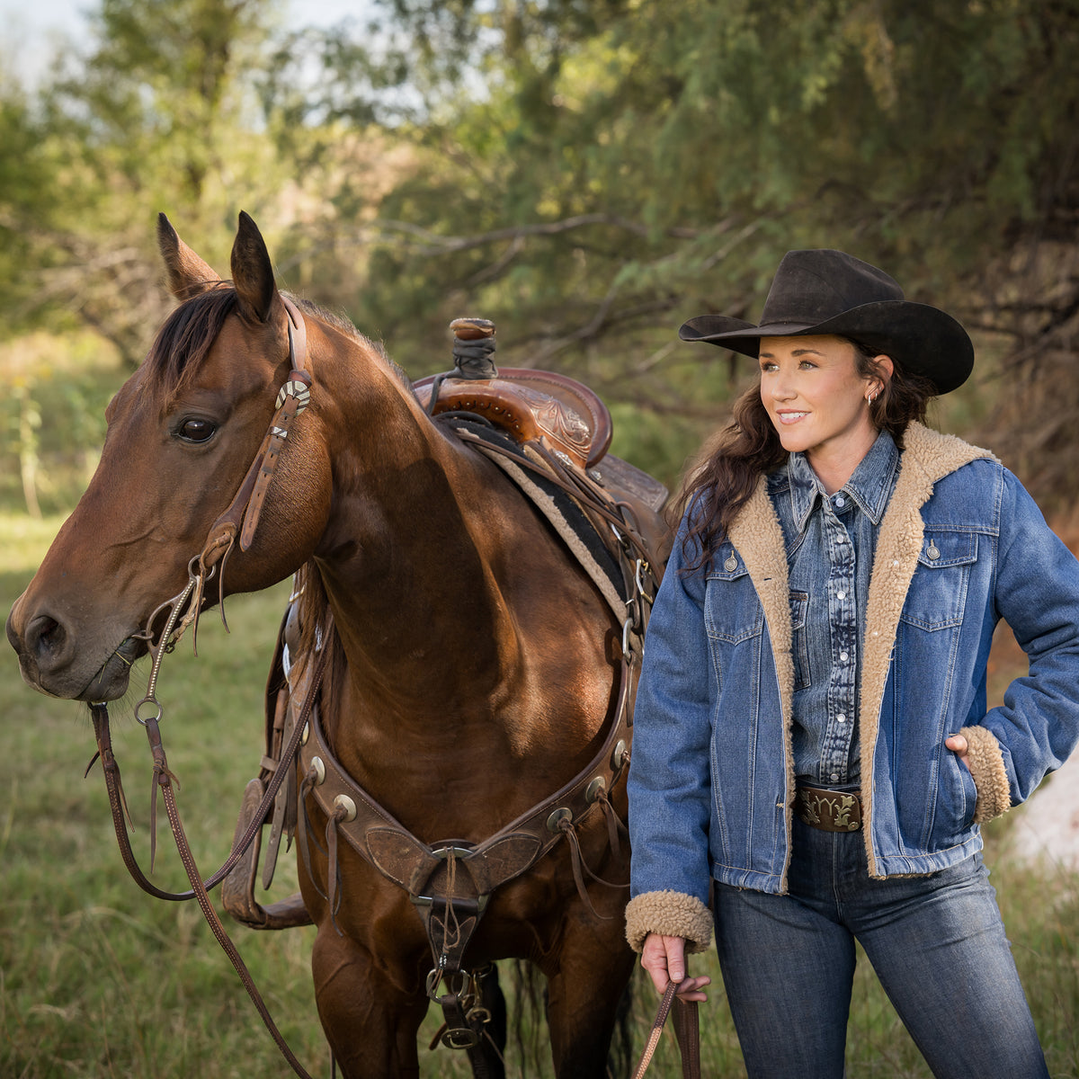 Yaleigh Yarbrough wearing our light wash denim lined with sherpa, two chest pockets and front button closure jacket next to a brown horse outside