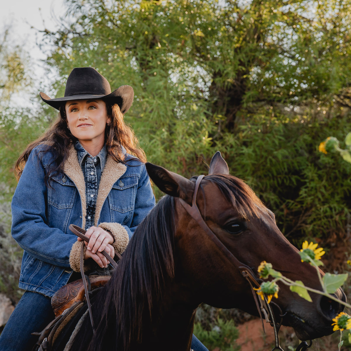 Yaleigh Yarbrough wearing our light wash denim lined with sherpa, two chest pockets and front button closure jacket on a brown horse outside