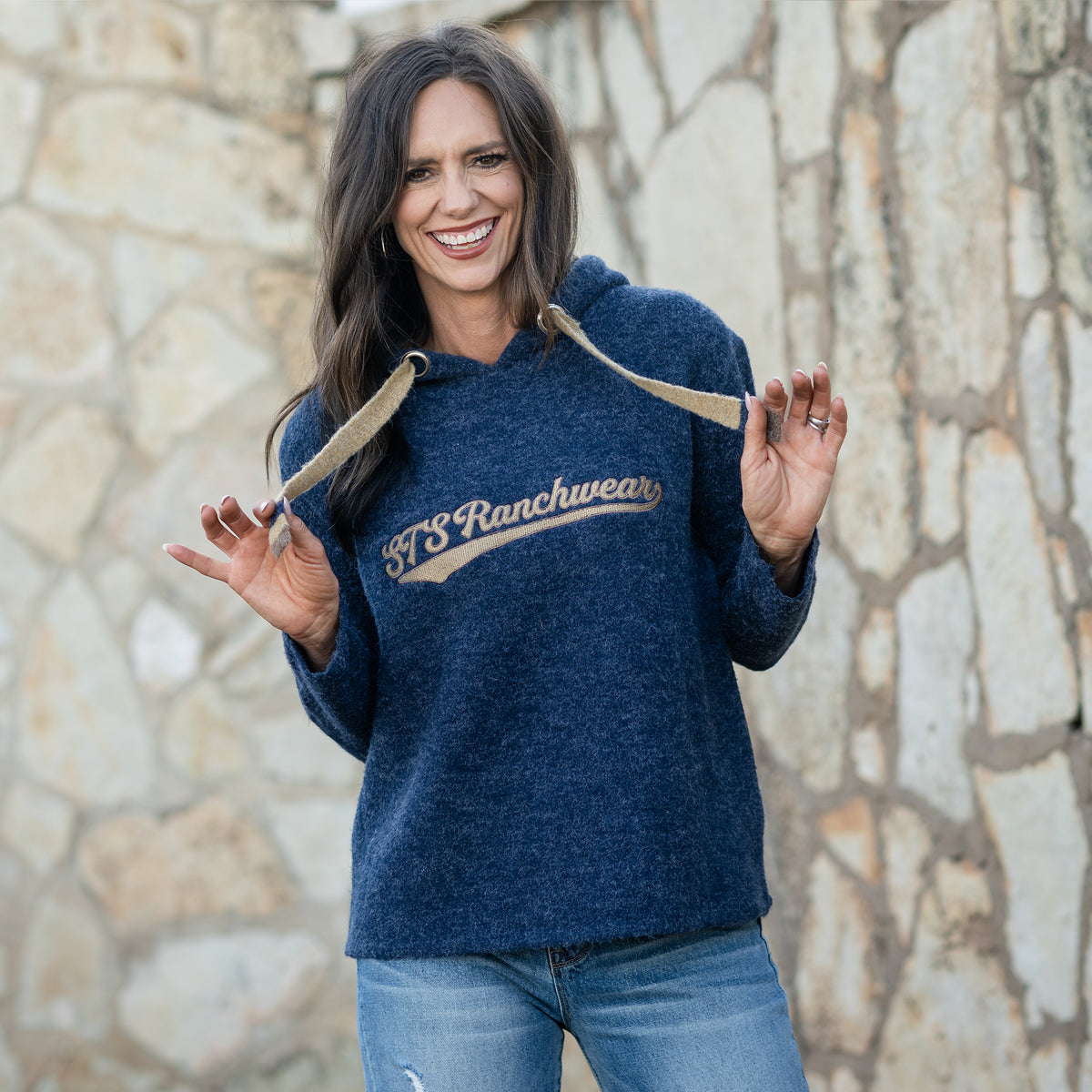Jen Smith wearing a navy hoodie with 'STS Ranchwear' logo on front and tan drawstrings for hood.