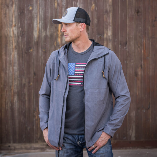 Man wearing a gray hat, tee shirt, jeans and a heather gray men's rain jacket with a hood and zip front closure.