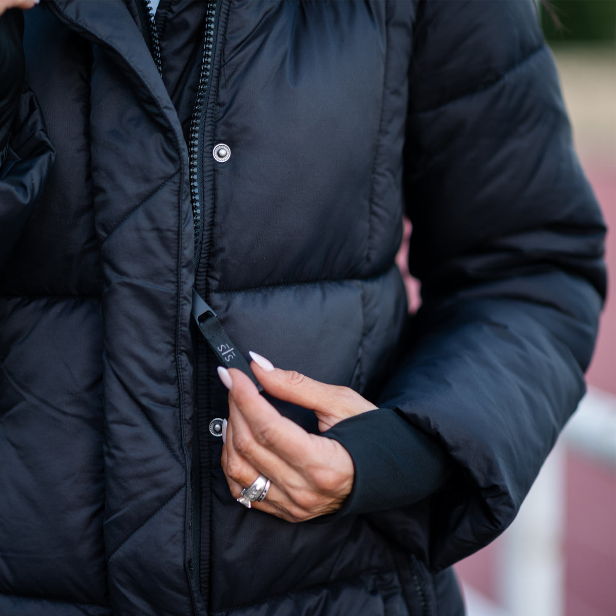 Person pulling the black zipper pull for the black puffer parka coat.