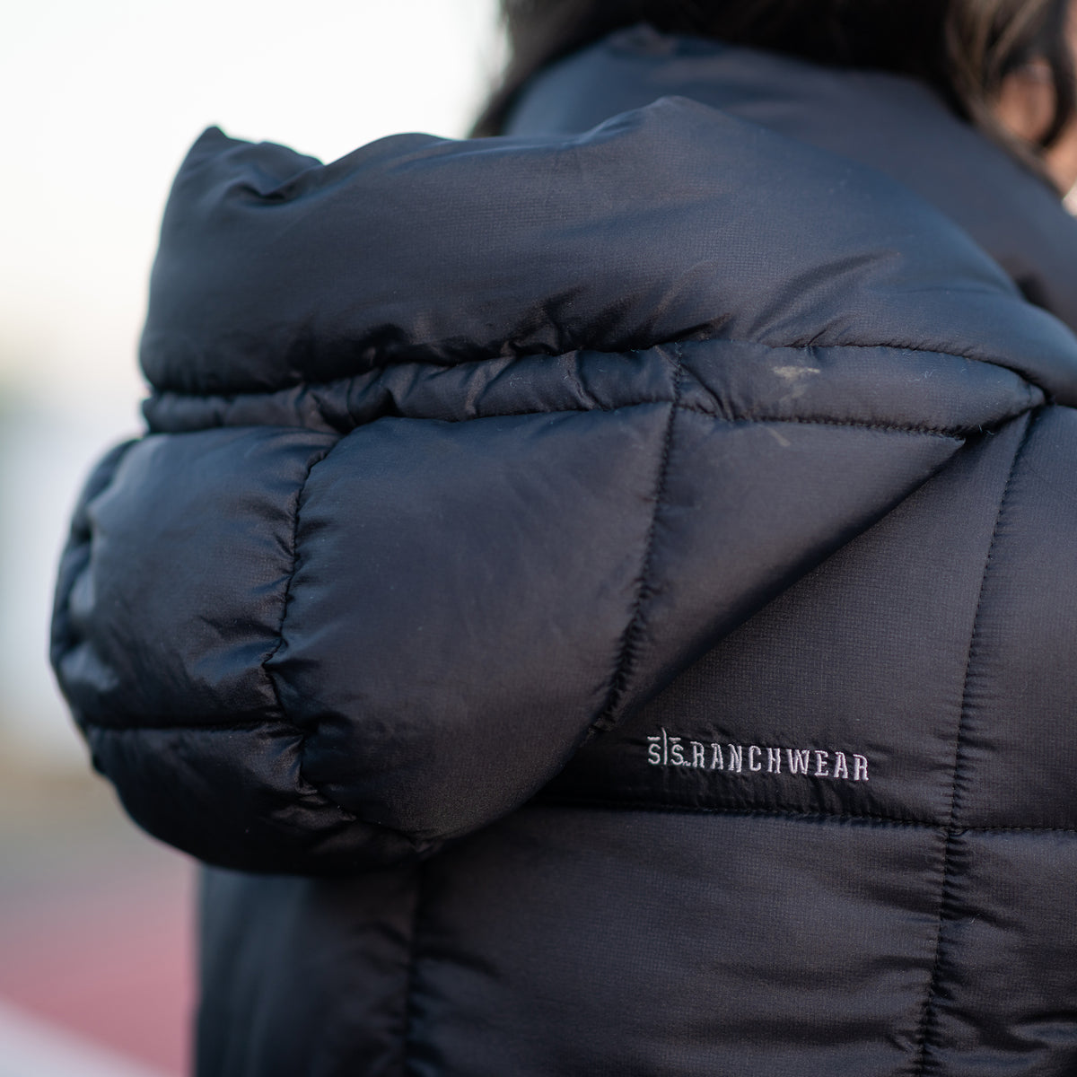 Black puffer parka coat hood with STS Ranchwear embroidery.