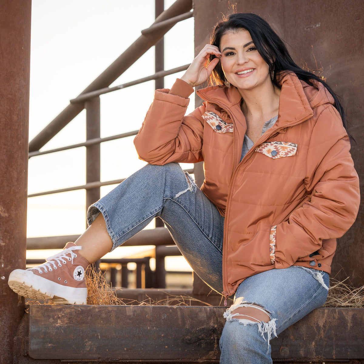 Whitney Vest wearing our rust collared puffer jacket with aztec detailing, zip front closure and removable hood outside.