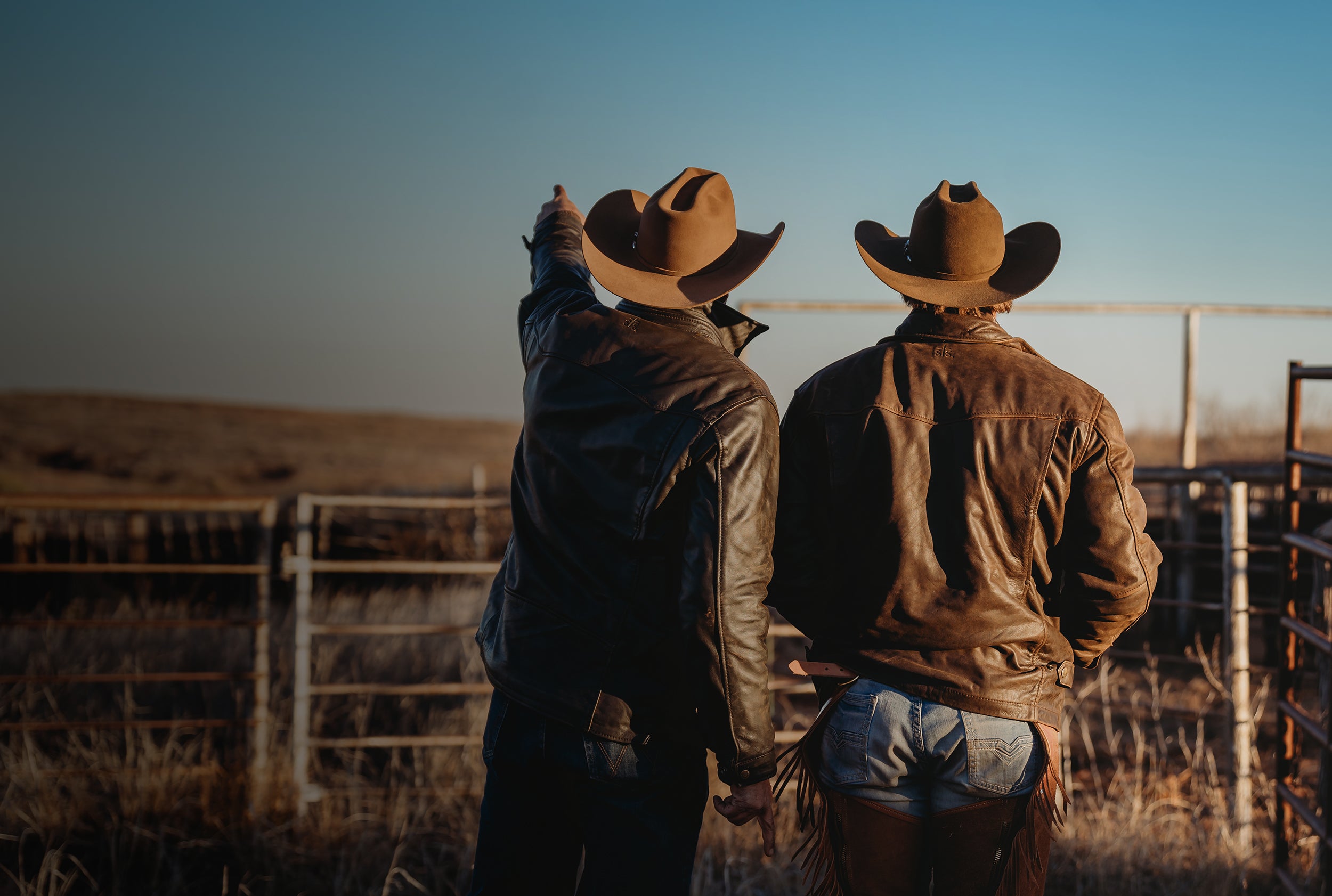 Two cowboys looking over the ranch wearing the men's Rifleman full grain leather jacket.