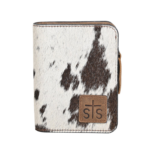 A wallet with brown and white hair on hide cowhide, zip around closure and brown leather patch with STS logo embossed on a white background.