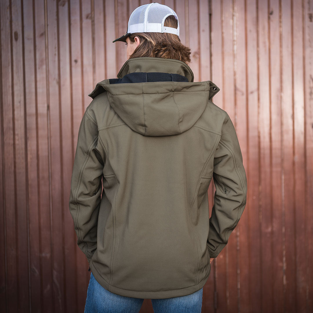 back of scout smith wearing our softshell olive green front zip closure jacket with removable hood in front of wooden door